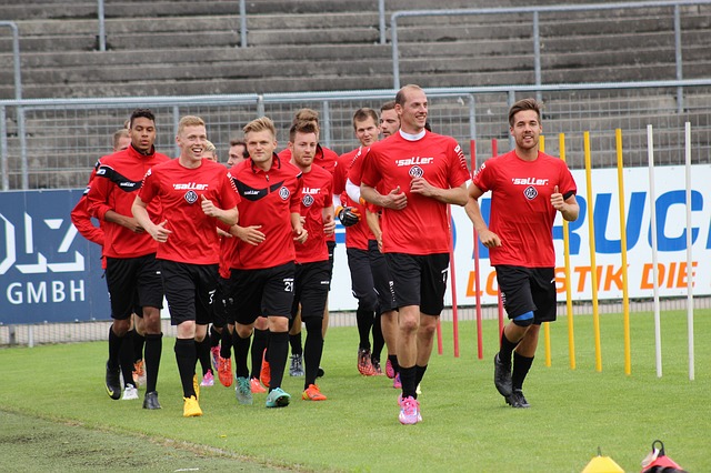 サッカー選手がトレーニング用具の周囲をグループでジョギングしている風景