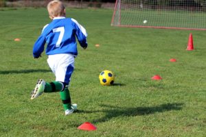 マーカーやパイロンを使ってサッカーのトレーニングをする少年